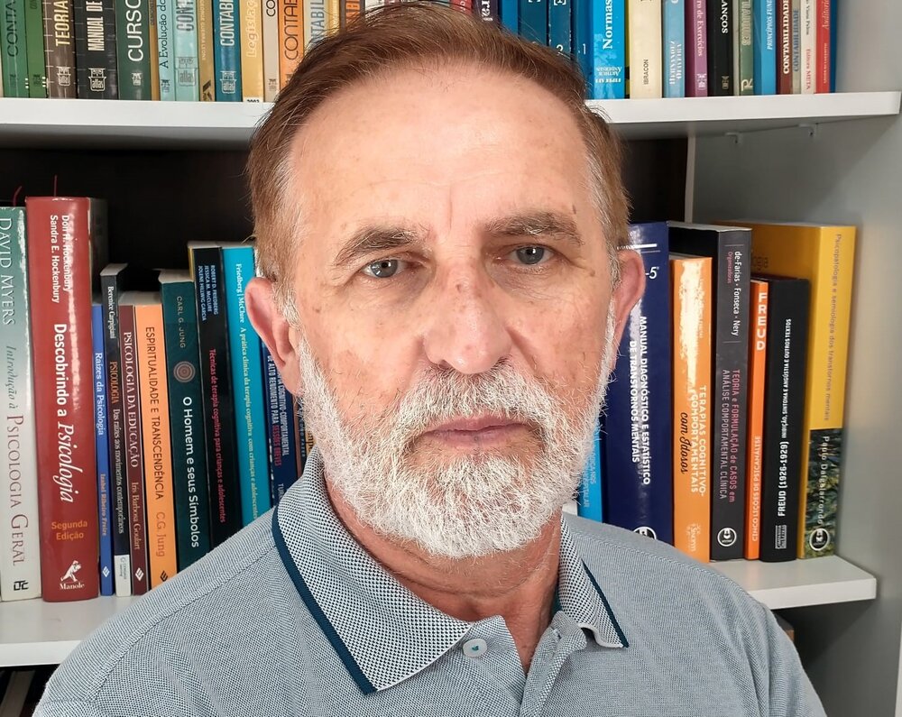 Geraldo Baranoski em frente a uma estante de livros